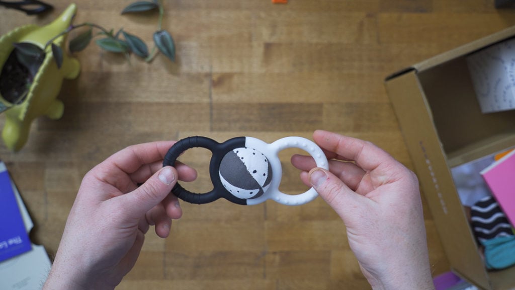 A close-up image of a black and white silicone rattle with a ball